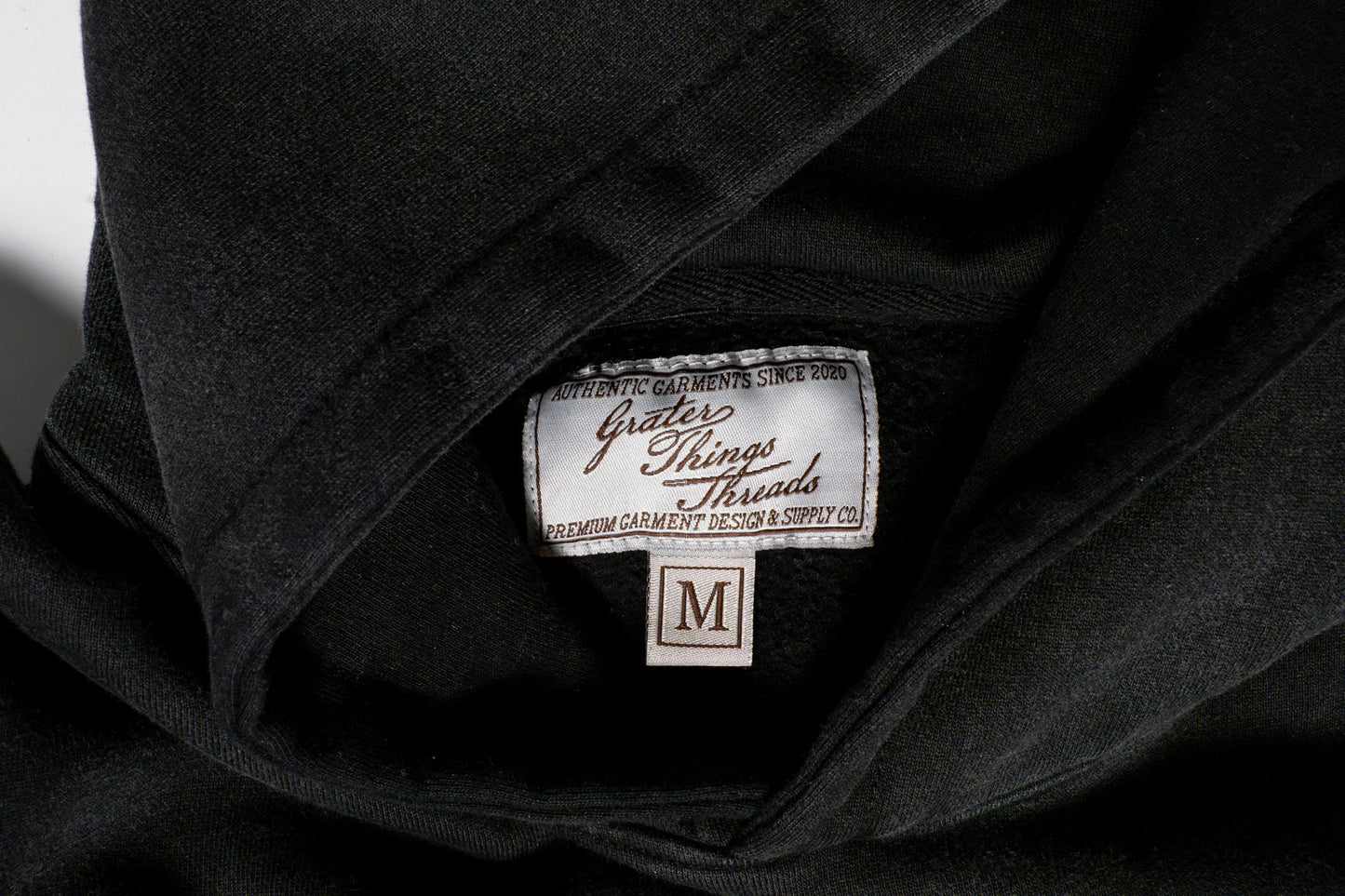 The tag reads Grater Things Threads in clean lettering, stitched neatly into the inner collar a subtle nod to comfort, quality, and cheesy charm.