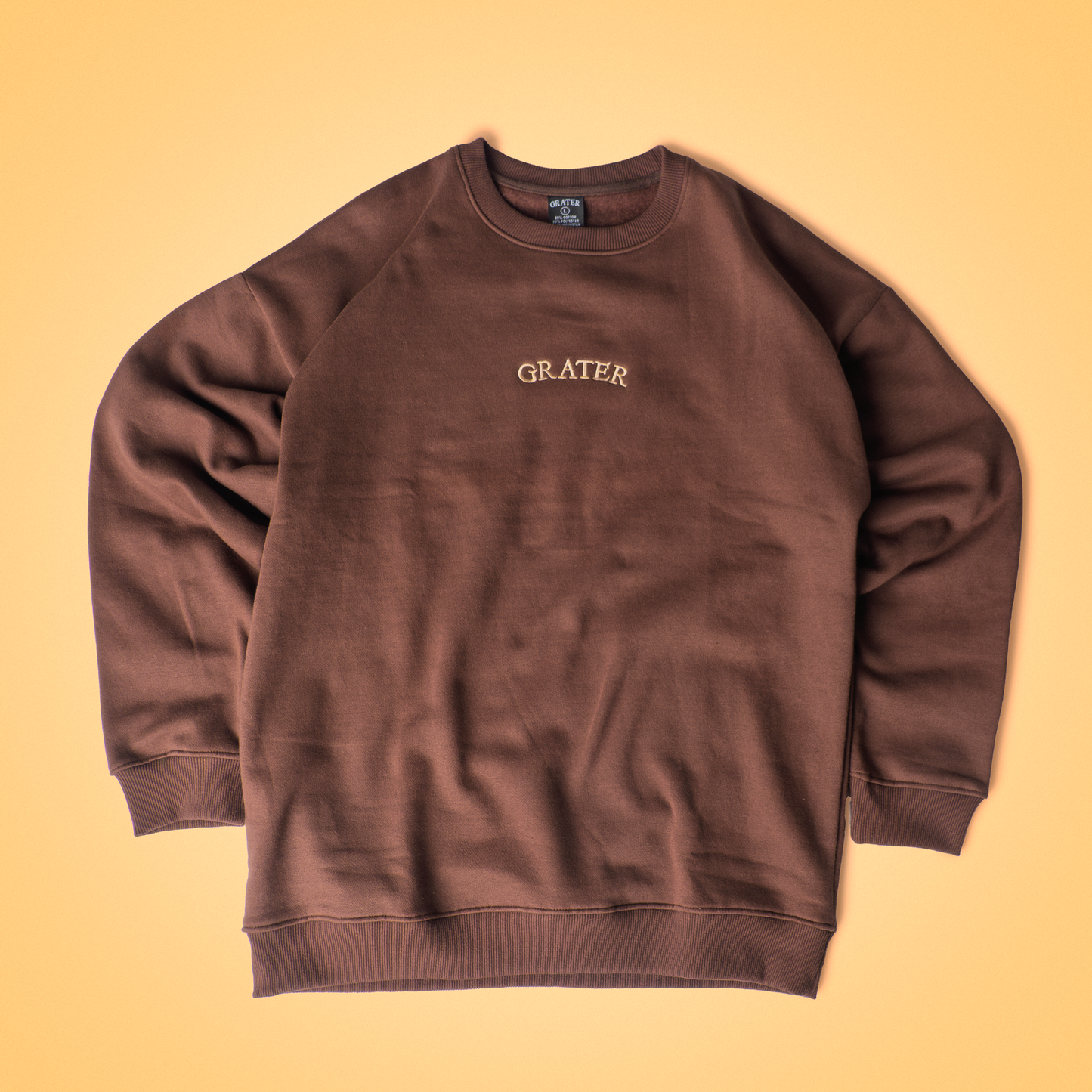 Fudge brown crew neck sweatshirt with ‘Fudge Fromage’ embroidered on the chest, ultra-soft fleece lining, and relaxed fit – a cozy, cheesy classic from the Grater Things collection.